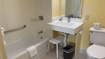 Un baño con bañera, lavabo, inodoro y un cubo de basura.