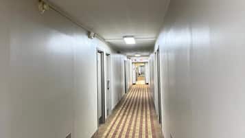 A long, narrow hotel corridor with patterned carpet, white walls, and doors on both sides.