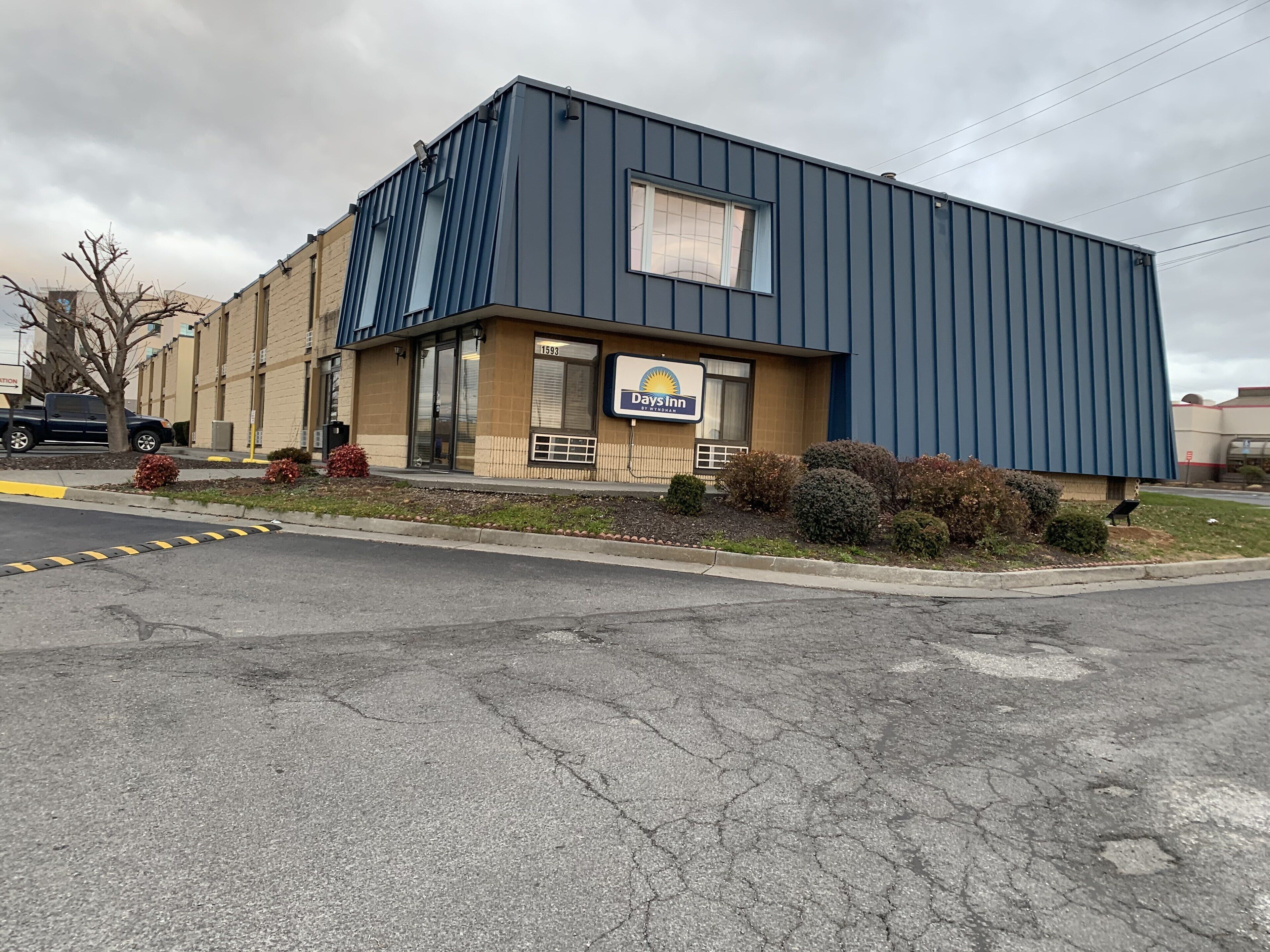 A Days Inn building with a blue exterior, a parking lot, and a sign indicating the address 1593.