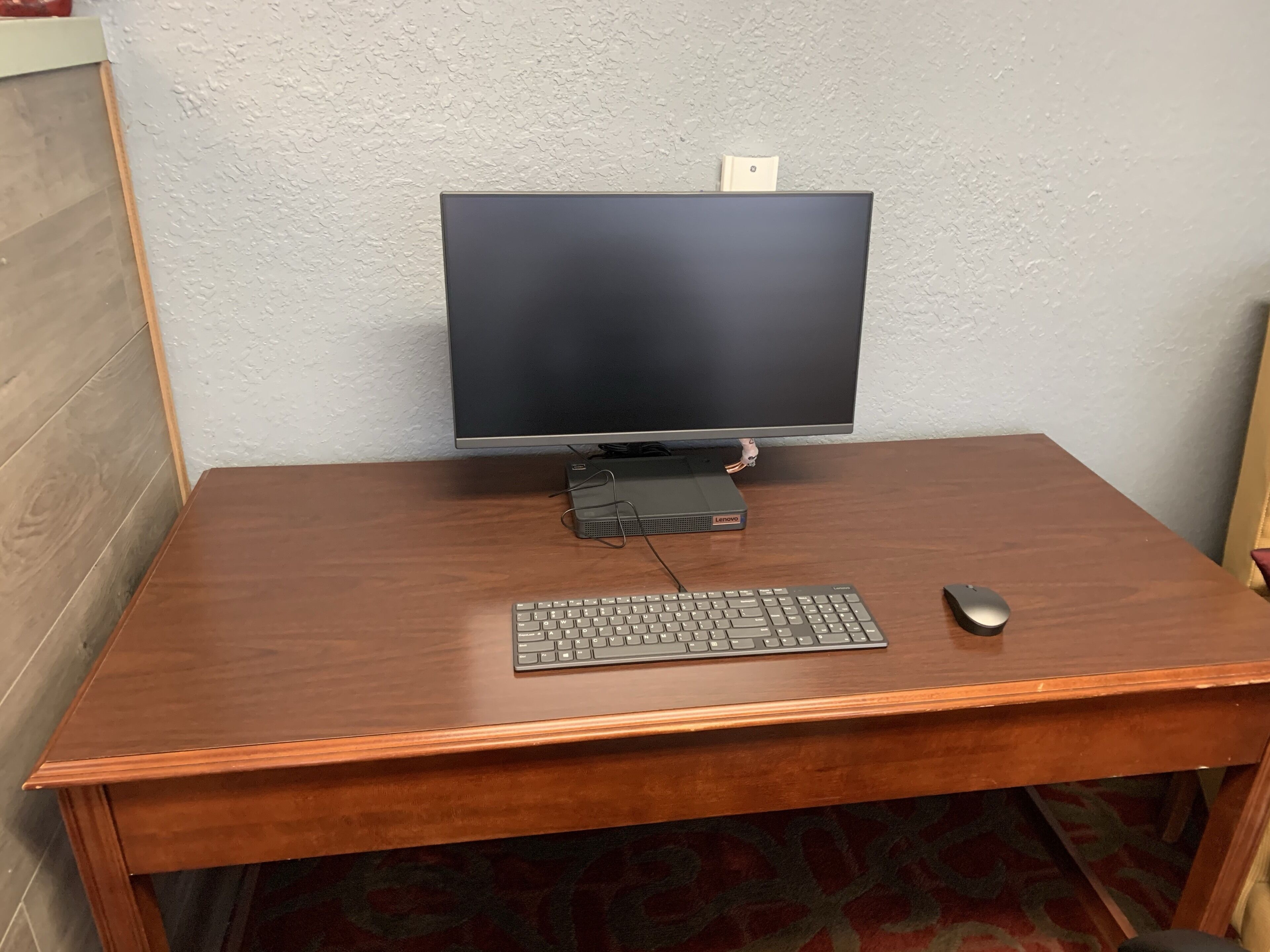 Un escritorio de madera con un monitor de computadora, teclado y ratón.