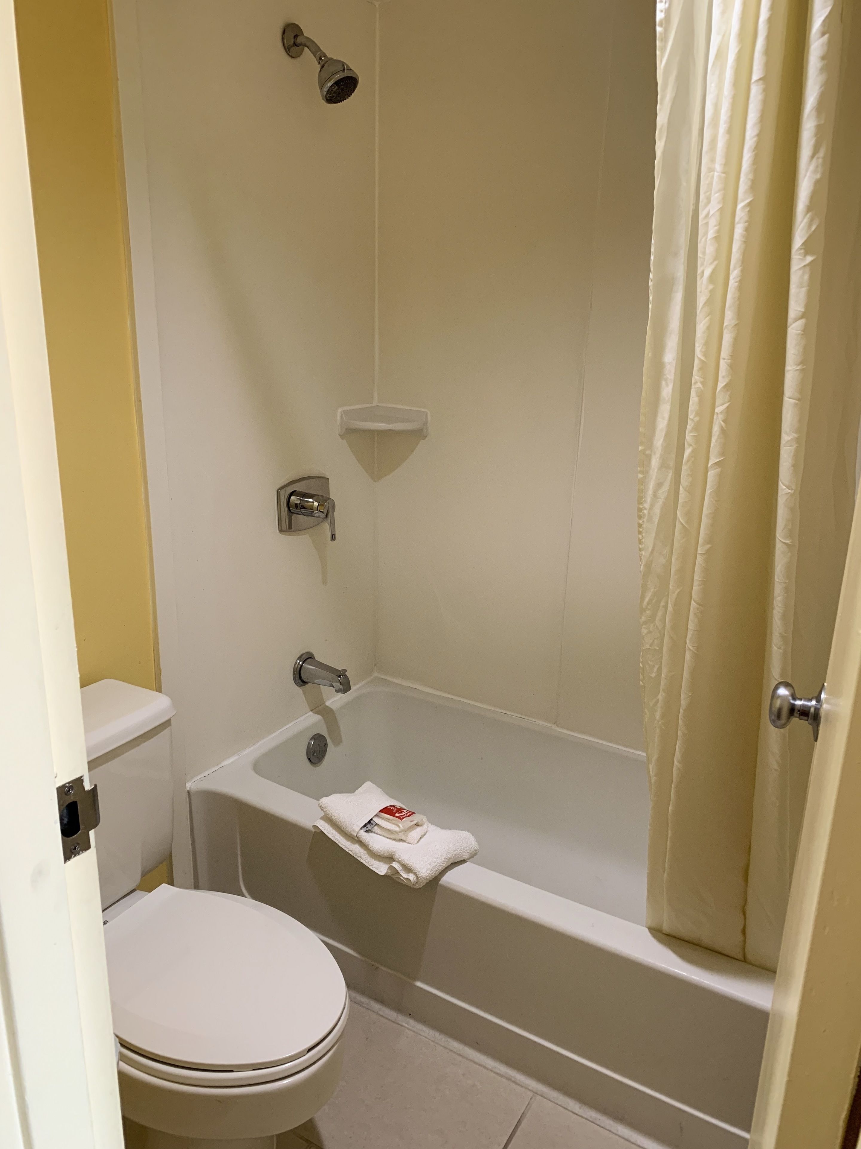 Een badkamer met toilet, bad en douchekop.