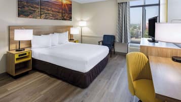 Een hotelkamer met een groot bed, twee nachtkastjes met lampen, een bureau met stoel en een televisie.