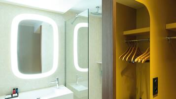 A bathroom with a white sink, a mirror, and a shower.