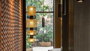 Un interior moderno con un diseño geométrico en la pared, una zona de bar de madera y vistas al exterior con vegetación.