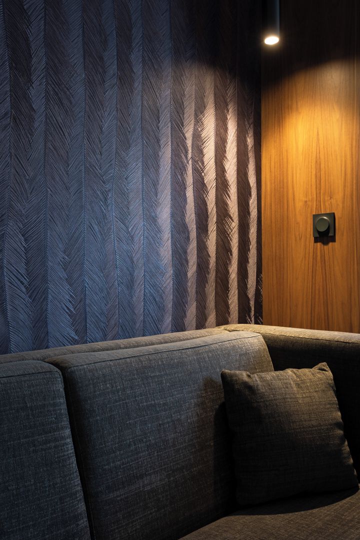 A room with a sofa, patterned wallpaper, and a wooden accent wall.