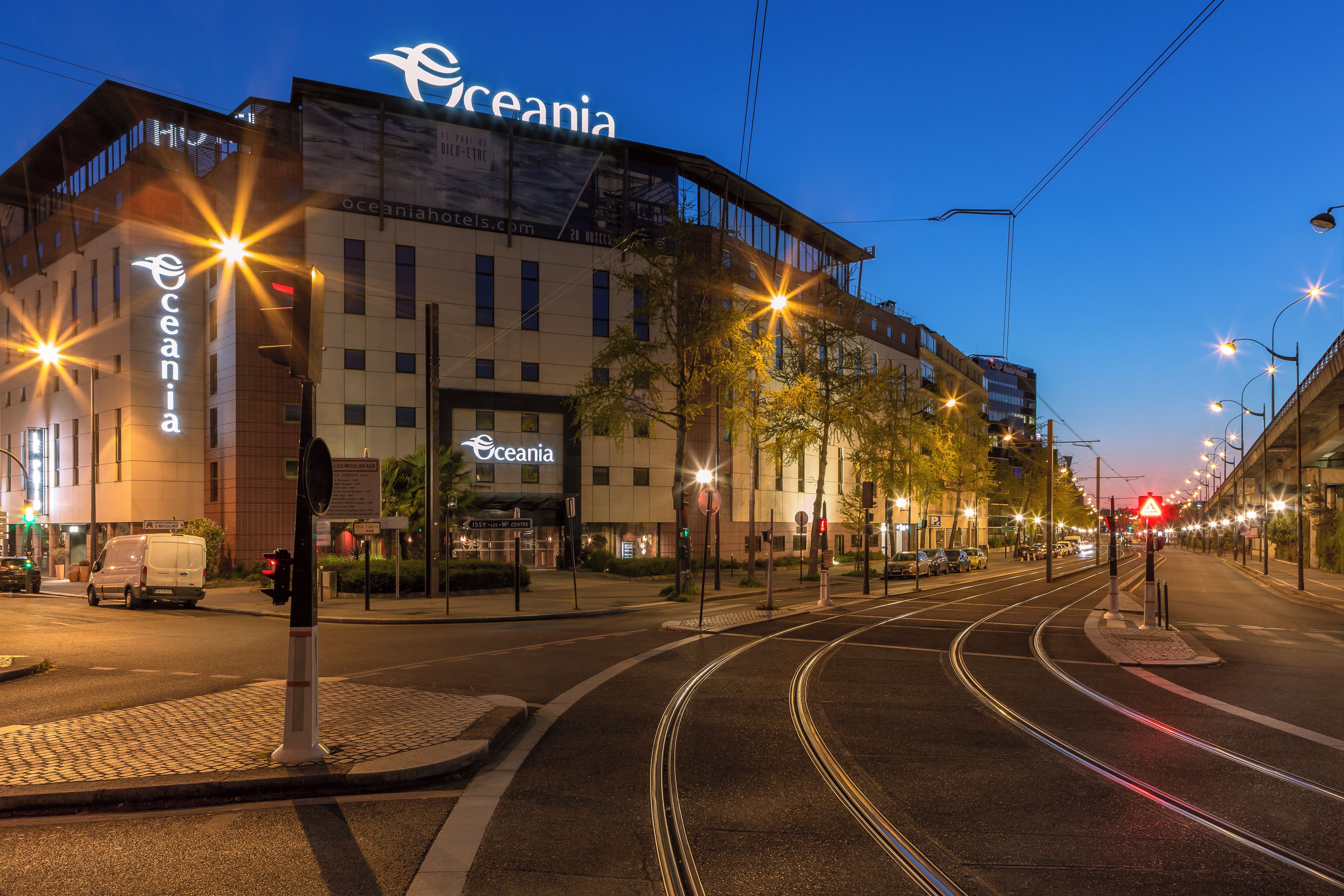 Een hotel met een opvallend bord, een tramlijn en een heldere lucht.