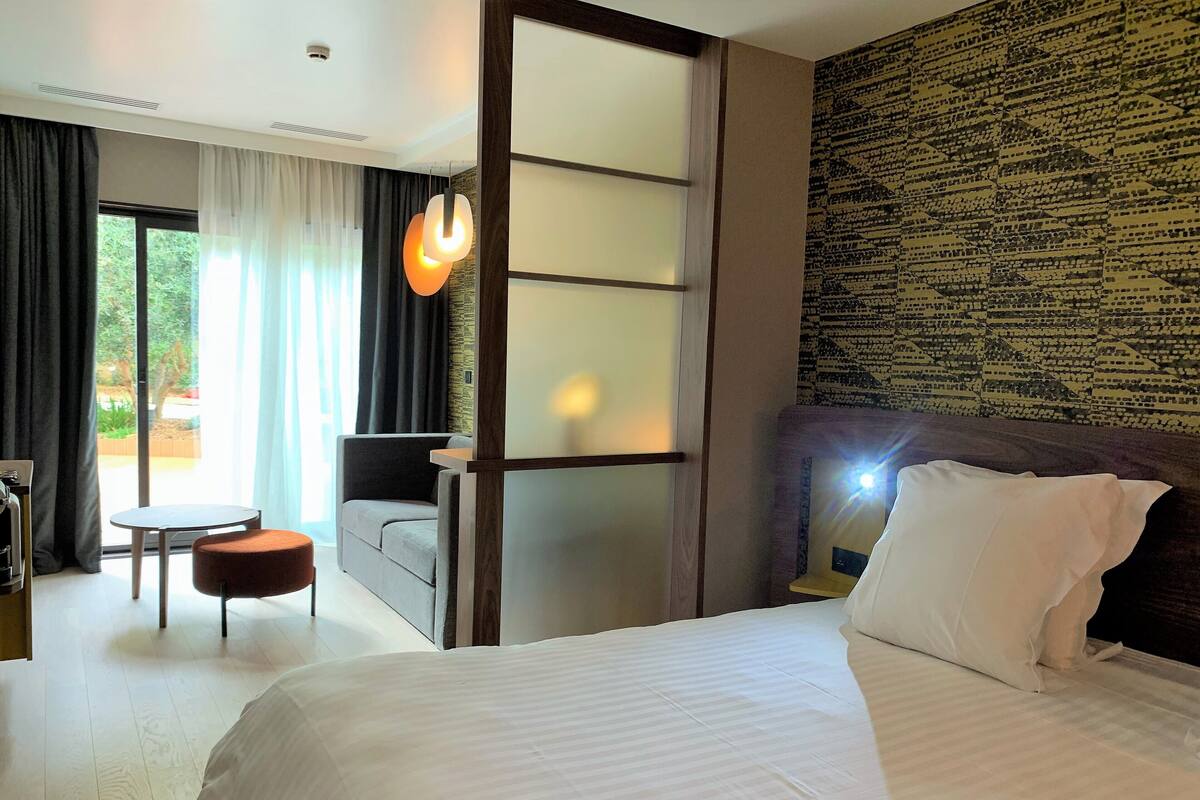 Une chambre d’hôtel avec un grand lit, un canapé, une petite table et une vue sur l’extérieur.