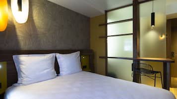 Une chambre d’hôtel avec un grand lit, un bureau et une chaise.