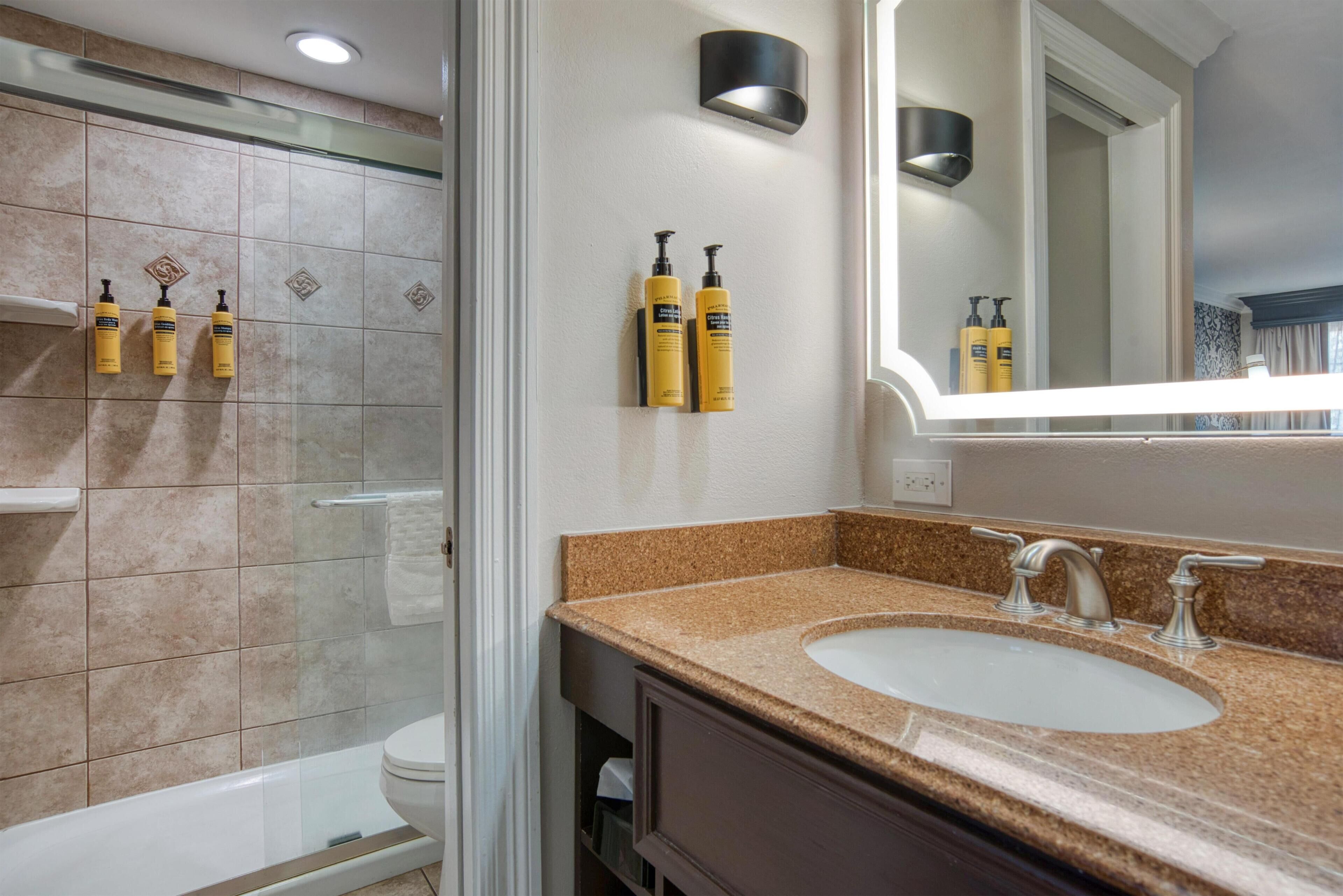 Une salle de bain avec un lavabo, un miroir et des articles de toilette fixés au mur.