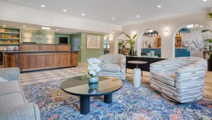 A spacious lobby with a central coffee table, seating area, and a reception desk.