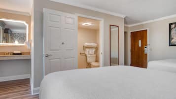 A hotel room with a large bed, a bathroom with a toilet and towel rack, and a wooden door.