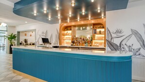 A modern bar area with a blue counter, wooden shelving, and a ceiling with recessed lighting.
