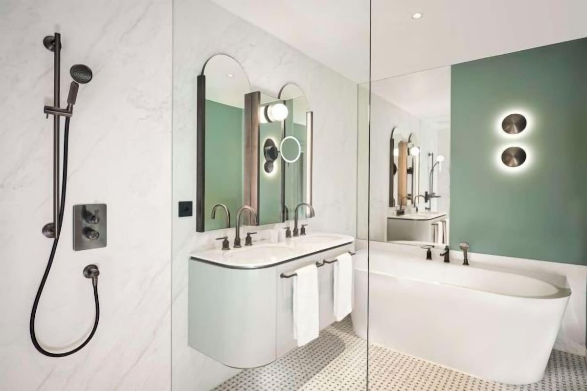 A modern bathroom with a glass-enclosed shower, a freestanding bathtub, and a vanity with two sinks.