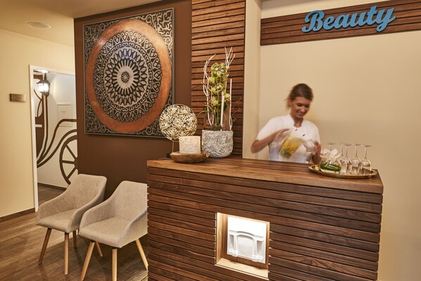 A reception desk with a wooden finish, a large decorative wall piece, and a sign that reads "Beauty".