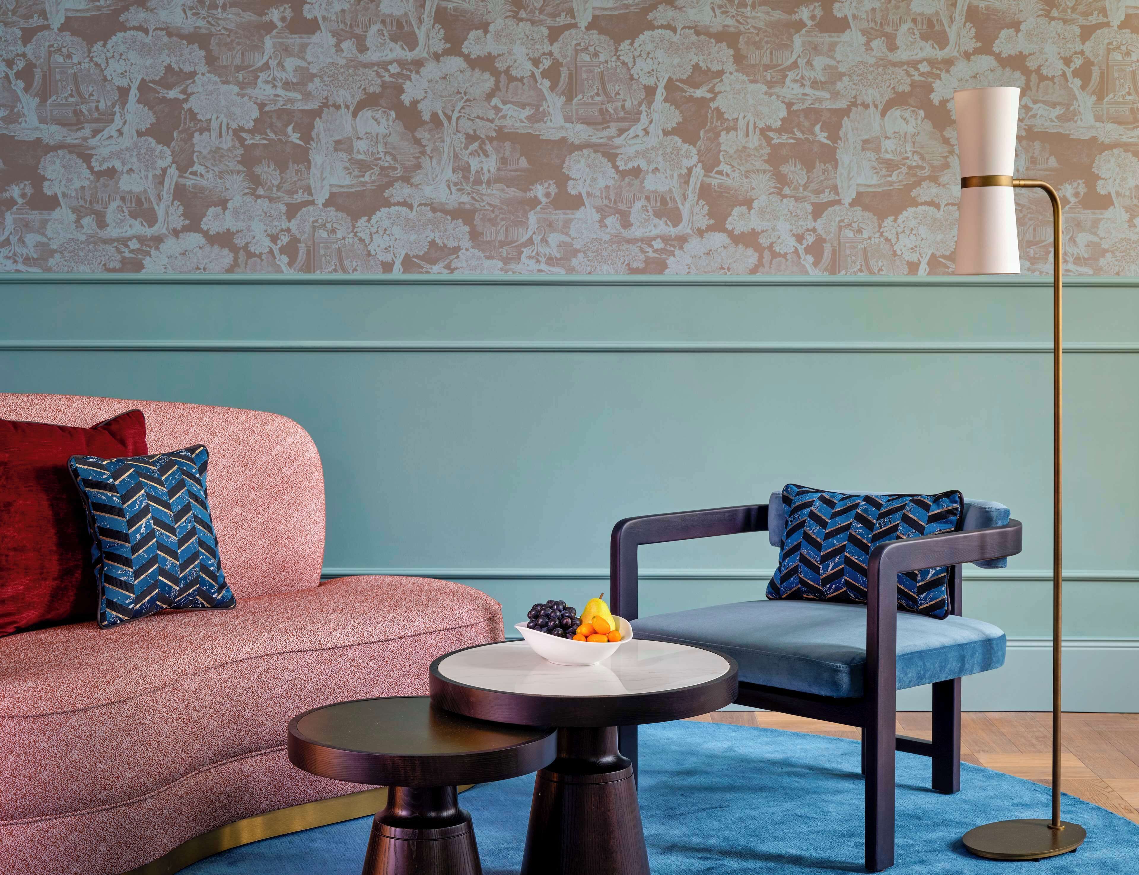A modern living room with a sofa, two chairs, a small round table, and a floor lamp.