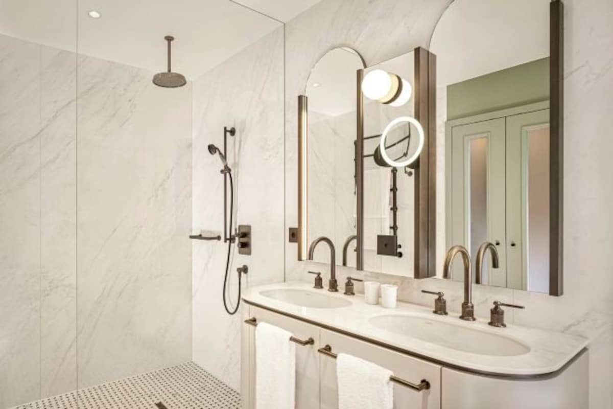 Un baño moderno con lavamanos doble, un espejo grande y una ducha.