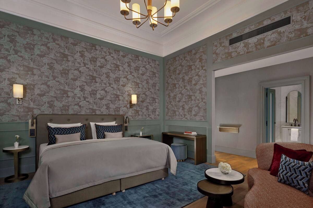 Ein Schlafzimmer mit einem großen Bett, Nachttischen, einem Schreibtisch, einem Stuhl und einem Spiegel.