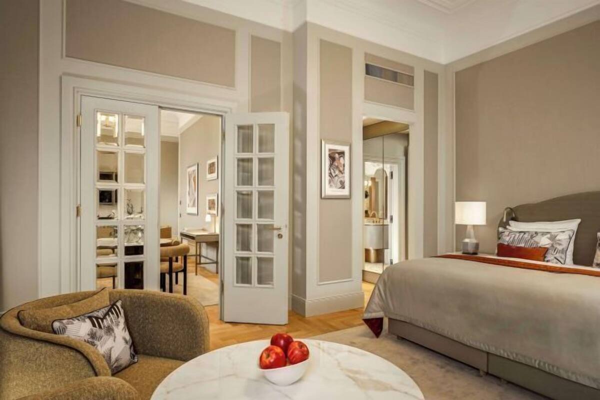 Ein Hotelzimmer mit Bett, einer Sitzecke mit Stuhl und Tisch sowie einem begehbaren Kleiderschrank.