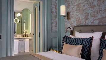 Habitación de hotel con cama, mesita de noche, espejo y baño con lavabo y toallero.