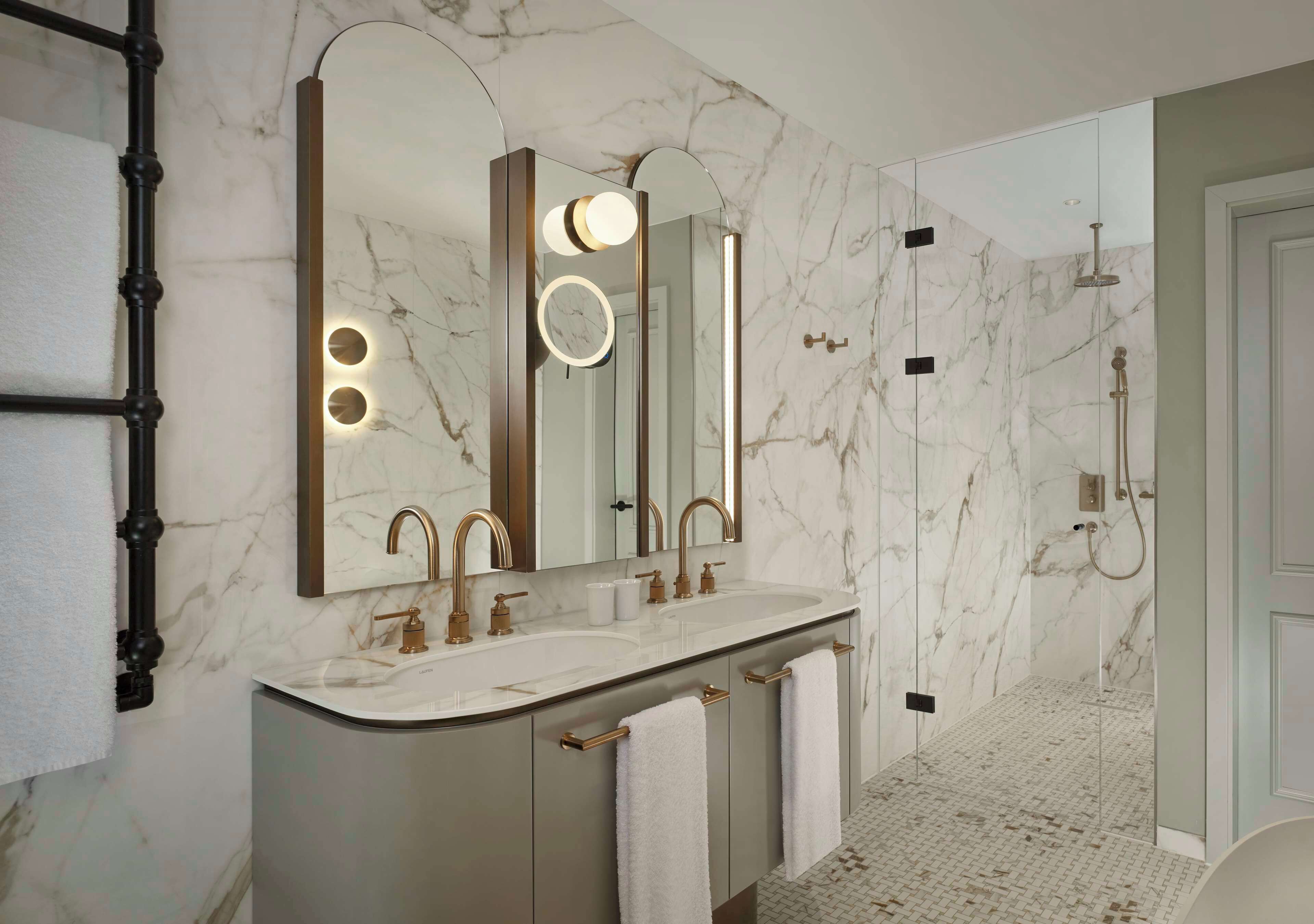 A modern bathroom with a marble backsplash, a double sink vanity, and a walk-in shower.