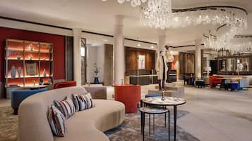 A spacious lobby with a large sofa, a round table, and a modern chandelier.