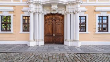 A building with a large wooden double door, flanked by white columns and ornate detailing.
