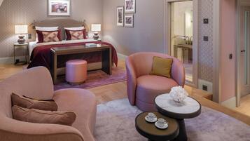 Une chambre à coucher comprenant un lit, des tables de chevet, une commode, une chaise, une table ronde et un petit tabouret.