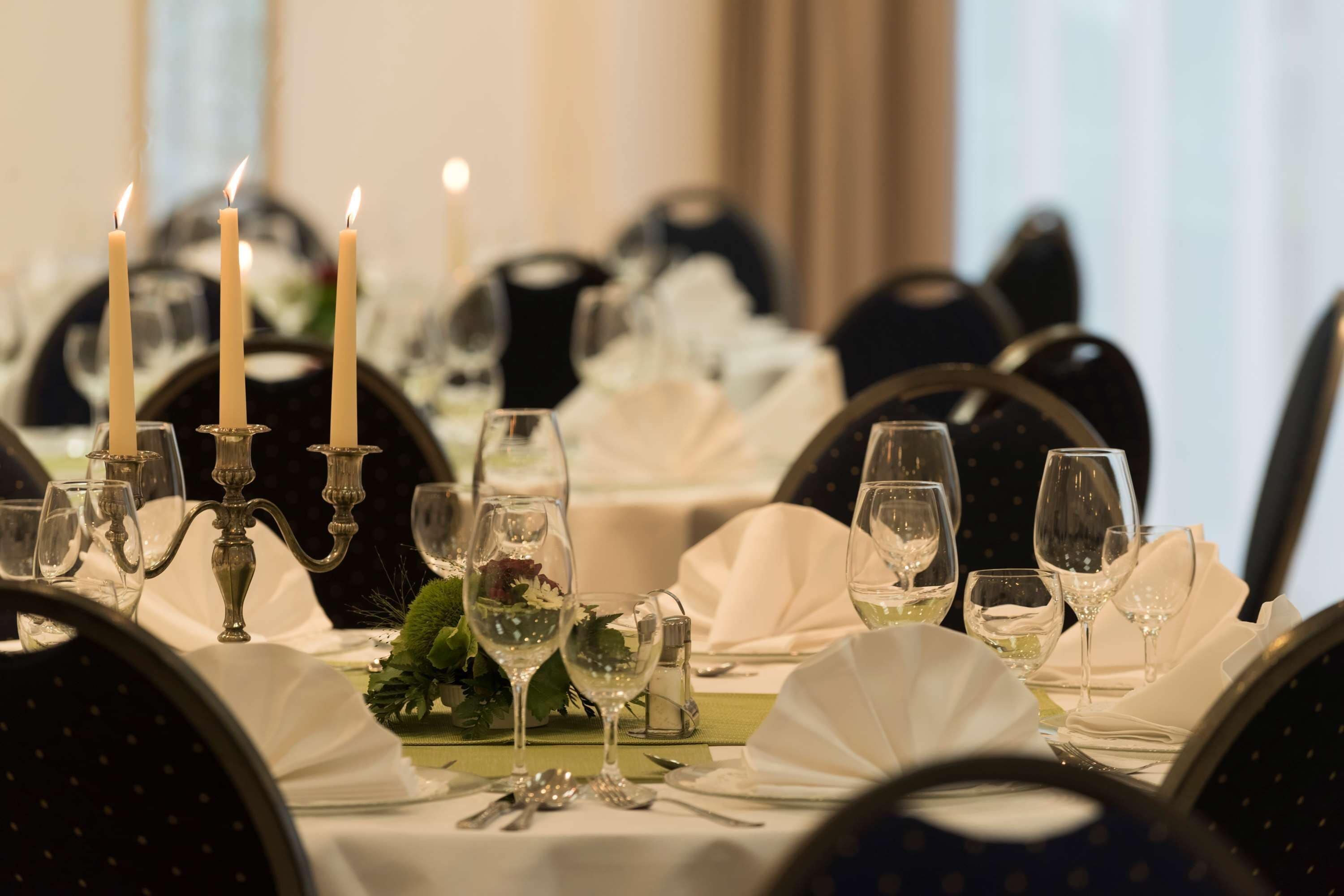 Une table à manger dressée de manière élégante, avec des bougies, des verres et des couverts, ce qui suggère un restaurant ou un cadre de banquet.