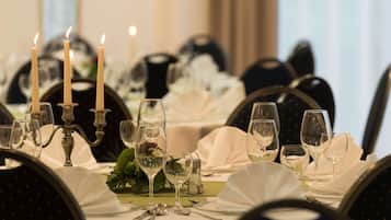 Une table à manger dressée de manière élégante, avec des bougies, des verres et des couverts, ce qui suggère un restaurant ou un cadre de banquet.