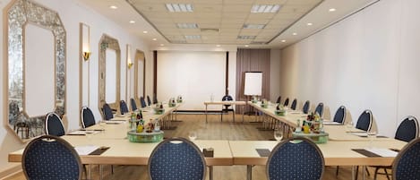A conference room with a long table, multiple chairs, and a large mirror on the left wall.