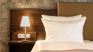 Una cama bien tendida, con un almohadón blanco y un cabecero de madera.