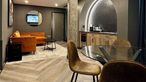 A modern living room with a sofa, a coffee table, and a glass-top dining table. - Carriage House Hotel & Conference Centre (Calgary)