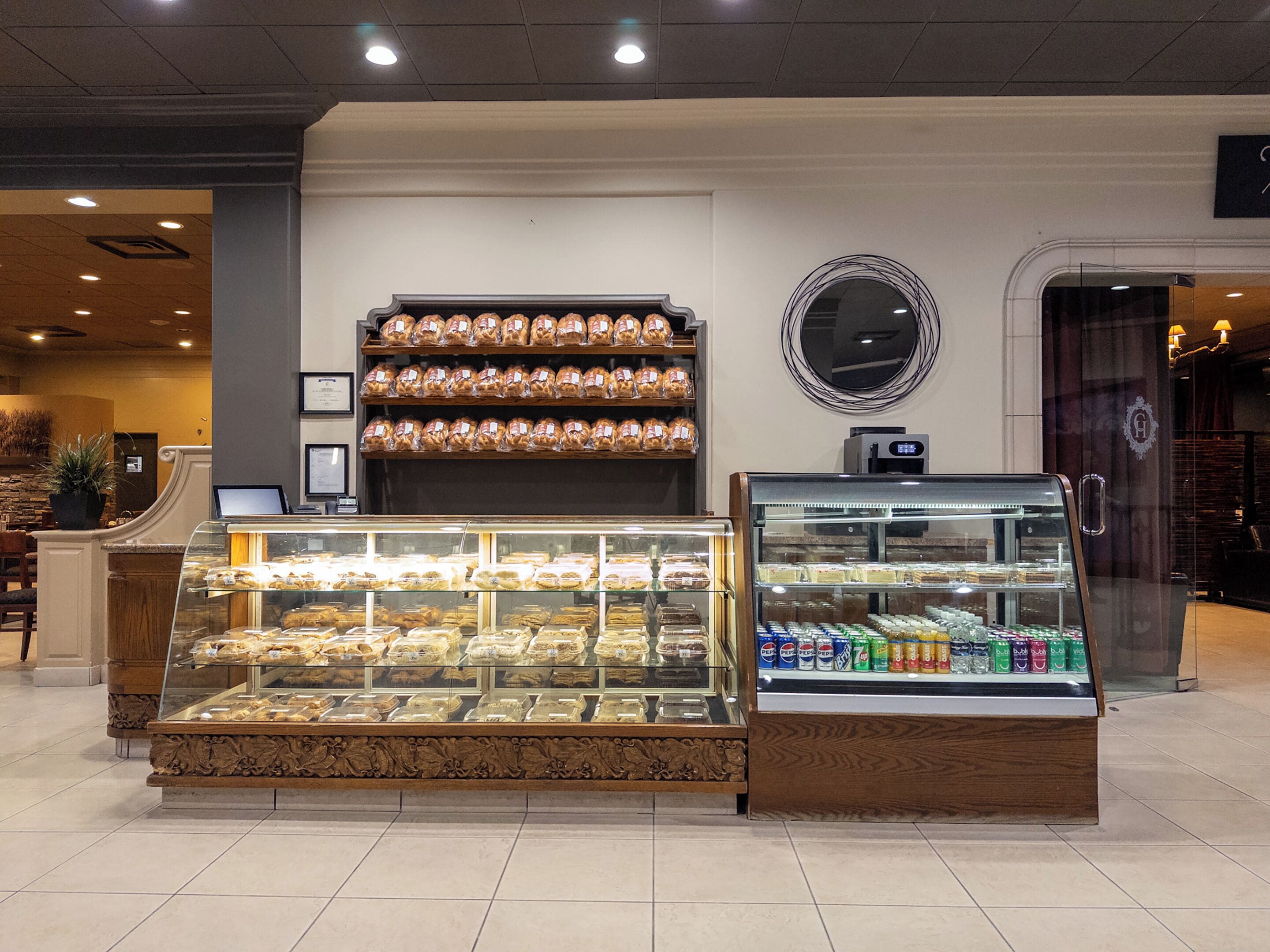 Una vitrina de panadería con diversos productos horneados y una sección refrigerada con bebidas.
