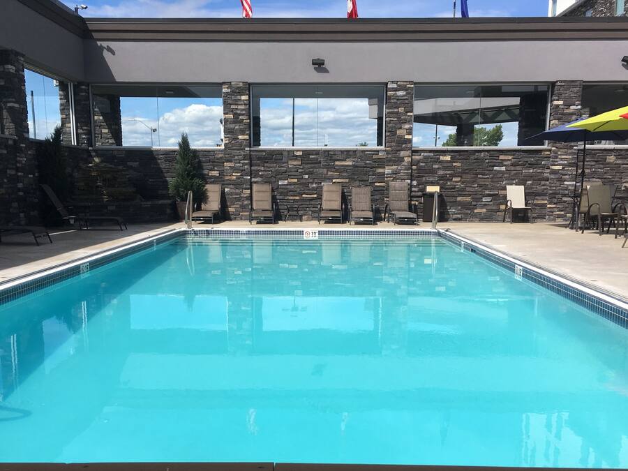 Une piscine avec des murs en pierre et plusieurs chaises longues.