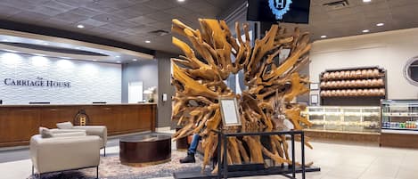 A reception area with a wooden sculpture centerpiece, a reception desk, and a bakery display.