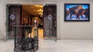 The entrance to Ninety Thirty Dining Lounge with a glass door, a chandelier, and a framed picture of bison on the wall. - Carriage House Hotel & Conference Centre (Calgary)