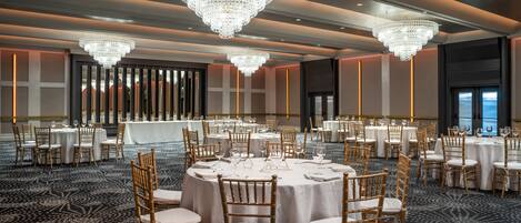 Un salón de banquetes con mesas redondas, sillas y candelabros.