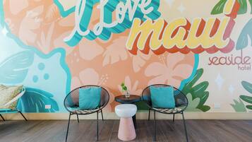 A room with a wall mural, two chairs, a small table, and a stool.