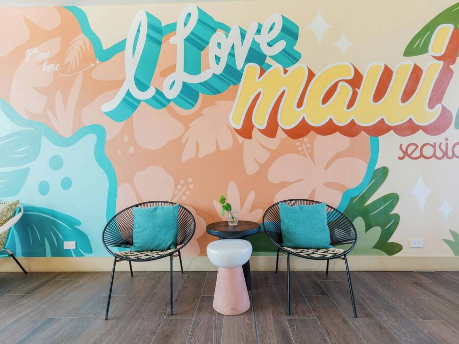 A room with a wall mural, two chairs, a small table, and a stool.