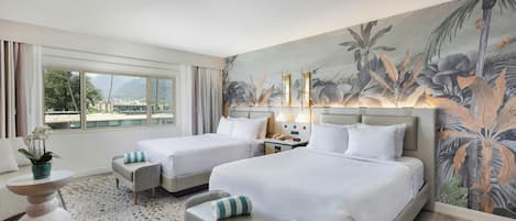 A hotel room with two beds, a sofa, a small table, and a large window.