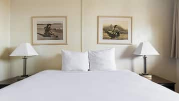 Une chambre d’hôtel avec un grand lit, deux lampes de chevet et deux tableaux encadrés au mur.