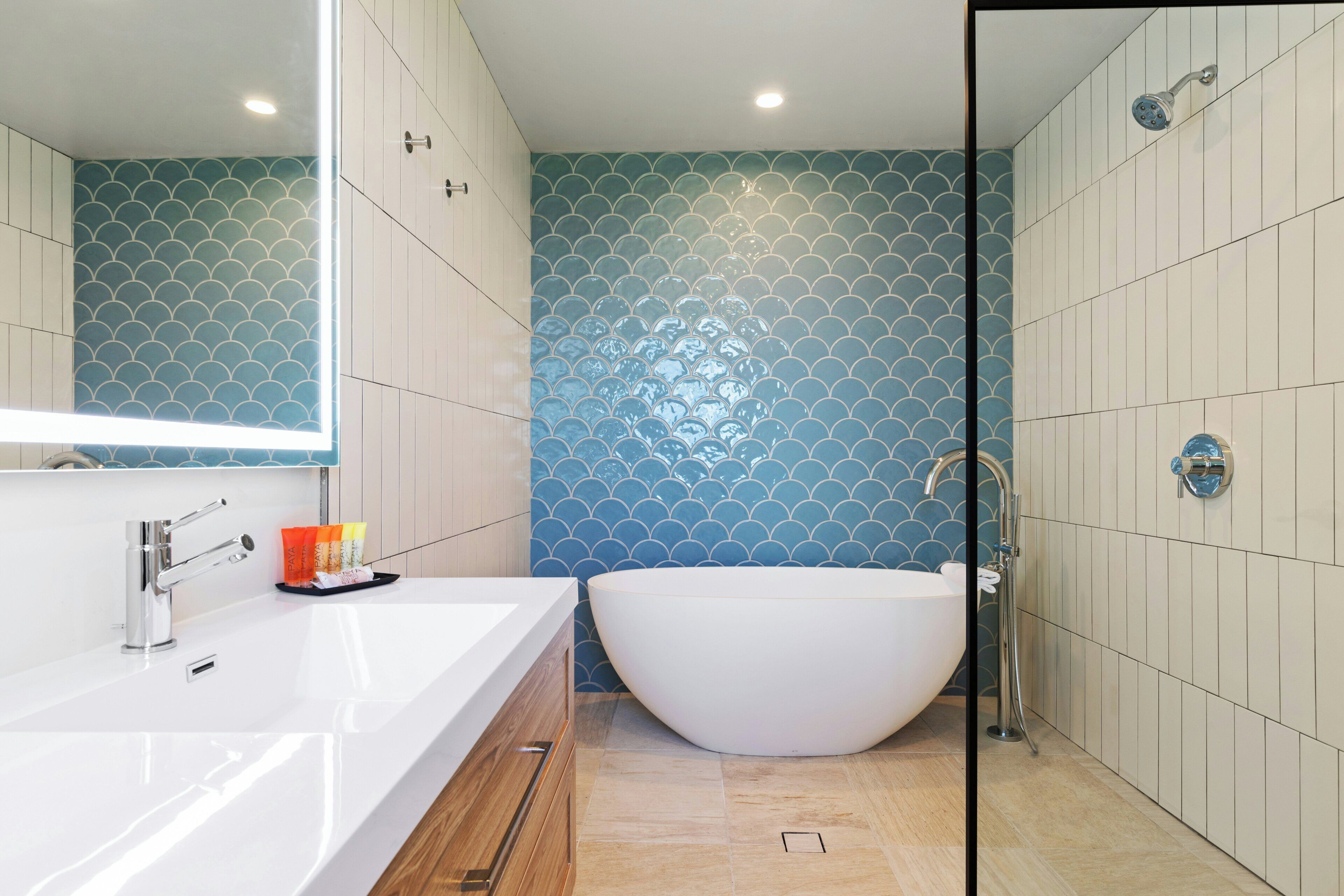Un baño moderno con una bañera grande, un lavabo blanco y una ducha.