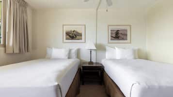 A hotel room with two beds, a nightstand, a lamp, and two framed pictures on the wall.