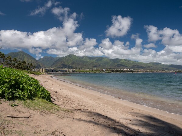 A beach with a clear view of mountains in the background, a sandy shore, and a calm sea. - Maui Seaside Hotel (Kahului)
