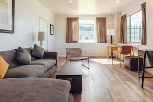 A modern living room with a sofa, a coffee table, a chair, a lamp, and a window with curtains.