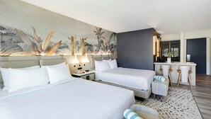 A hotel room with two beds, a small desk, and a large wall mural.