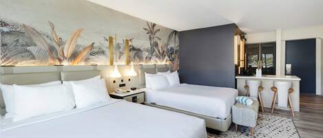 Habitación de hotel con dos camas, un escritorio pequeño y un mural grande en la pared.