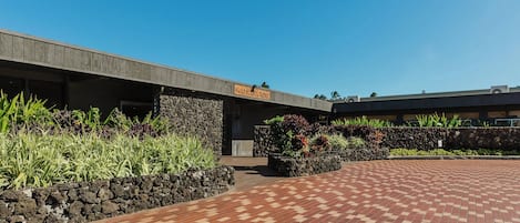 A hotel entrance with a stone wall and a paved walkway.