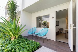 Entrada de hotel con un pequeño espacio al aire libre, una planta en maceta y una puerta que da a una habitación.