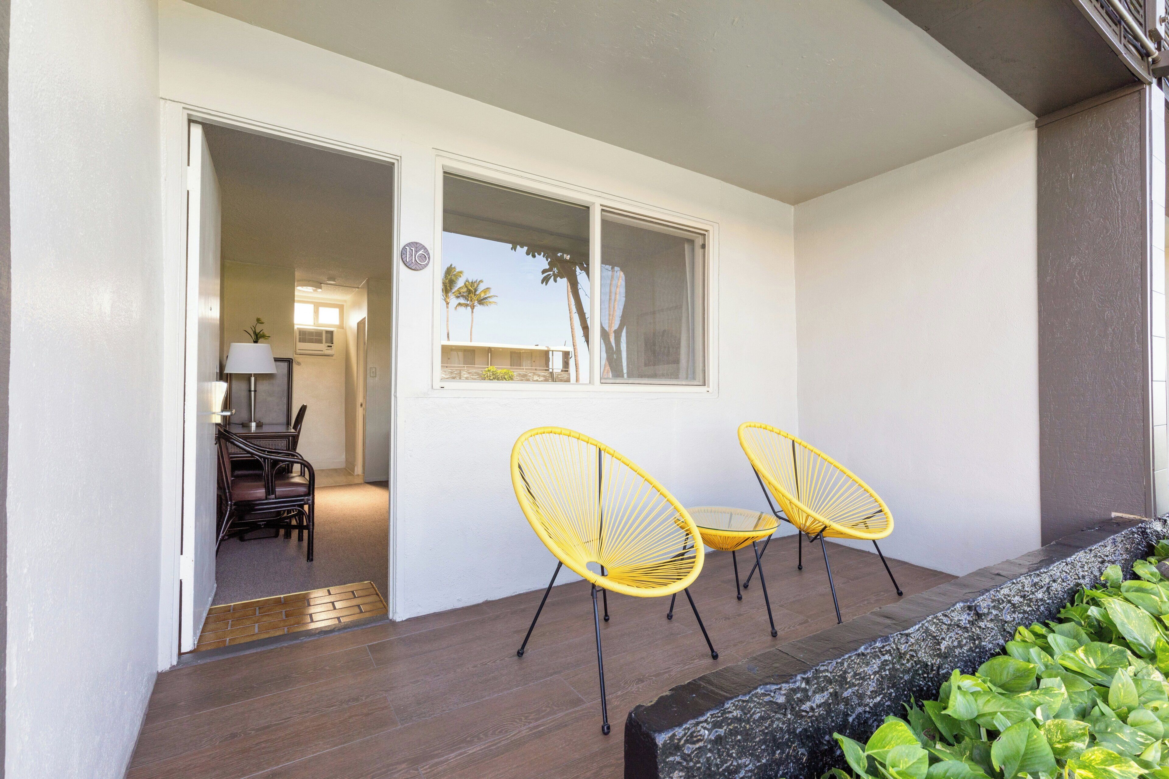 A room with a wooden floor, a window, and two yellow chairs.